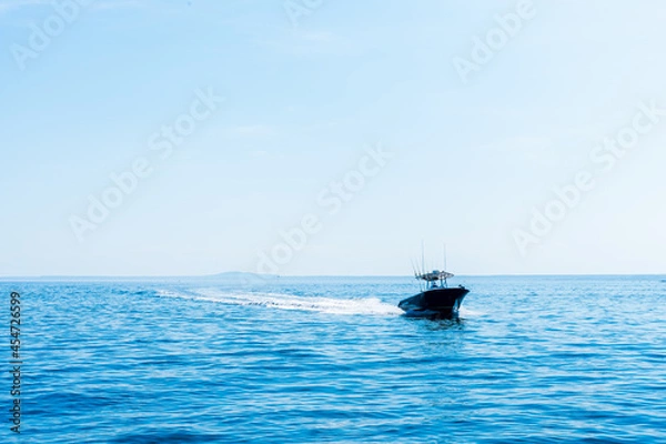 Obraz Small open black fishing boat with center console in motion in the early morning in the Atlantic Ocean
