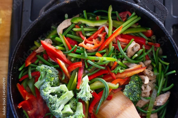 Obraz Coocing vegetables in a frying pan. Broccoli, carrots, string beans on cast iron frying pan. Vegetarian Food.