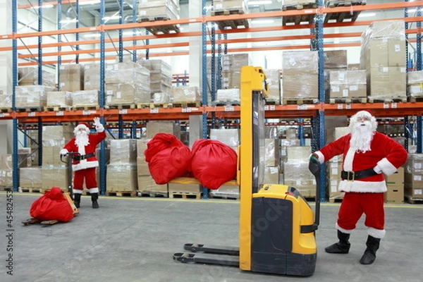 Obraz two santa clauses workers at work in large storehouse