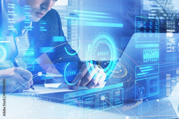 Fototapeta Businessman is taking notes in front of laptop with hologram