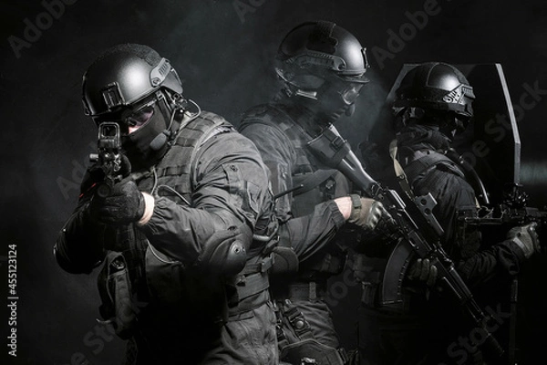 Fototapeta a special forces soldier as part of a special forces group covers the rear, aim at the camera using a laser sight.