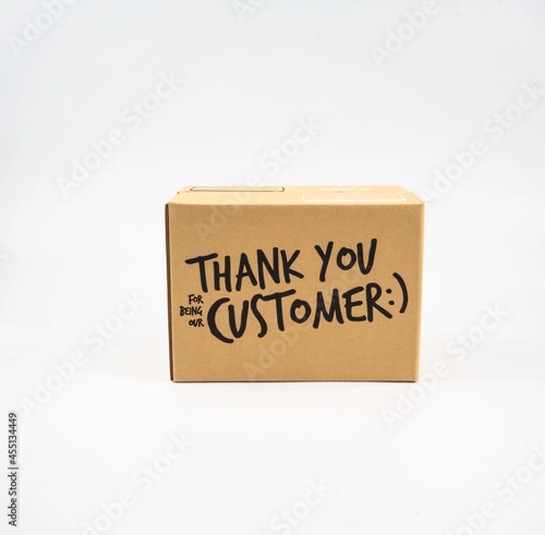 Fototapeta A closed cardboard box taped up, and there is a Thank you for being our customer beside the parcel box for delivery and shopping online concept design isolated on white background.