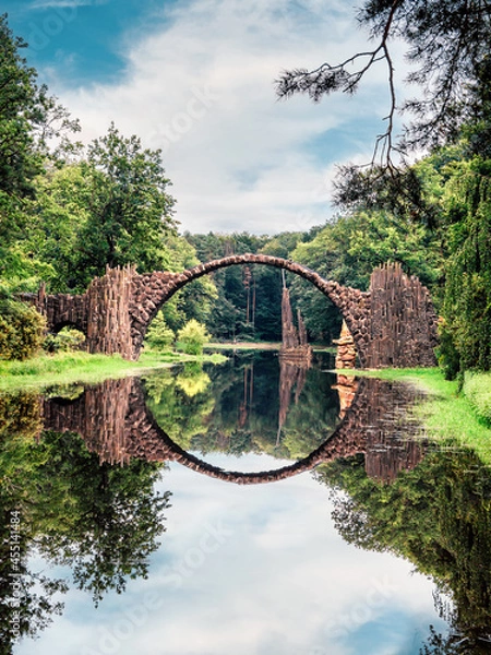 Fototapeta Rakotz Bridge, Rakotzbrucke in Kromlau, Saxony, Germany. Fantastic landscape in Azalea and Rhododendron Park Kromlau. Reflection of bridge in water of Rakotzsee. traveling and travel goals for tourism