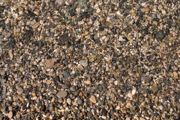 Obraz Pebble sea beach, brown wet pebbles covered by a wave