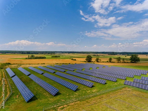 Obraz Photovoltaic farm - renewable energy from sunlight - photovoltaic panels set on a green field. Renewable energy supplying medium-sized enterprises