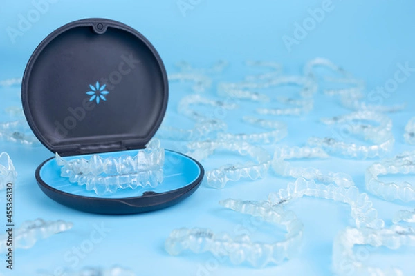 Obraz Invisible retainers case with orthodontic aligner brackets. Black plastic dental container for removable invisalign braces on blue background