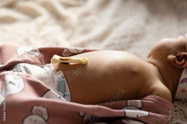 Fototapeta Newborn baby girl laying down with umbilical cord still attached - side view