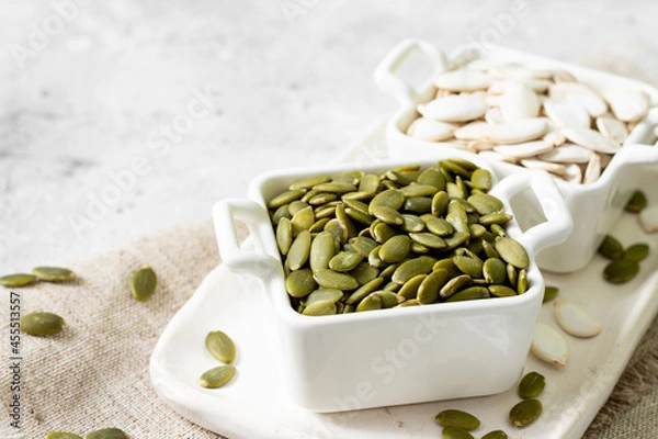 Obraz Pumpkin seeds in a white bowl on a light gray culinary background closeup