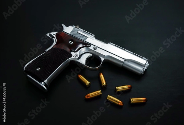 Fototapeta Close-Up handgun with golden sharp bullets on a black surface.