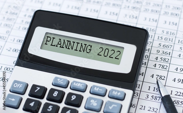 Fototapeta Text PLANNING 2022 on the calculator screen against the background of financial statements on the table