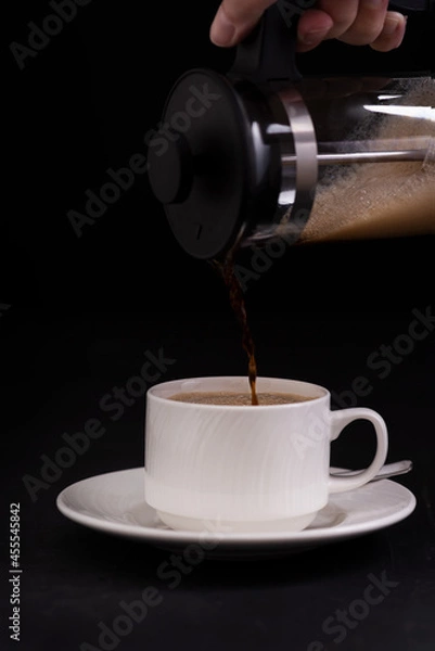Obraz Cup of coffee and a coffee maker on black background