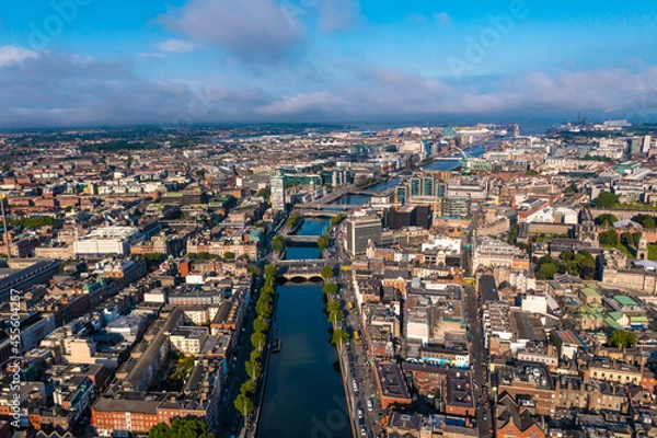 Obraz Establisher shot of Dublin skyline with river flowing with bridge connecting two sides of street surrounded by buildings during a cloudy day