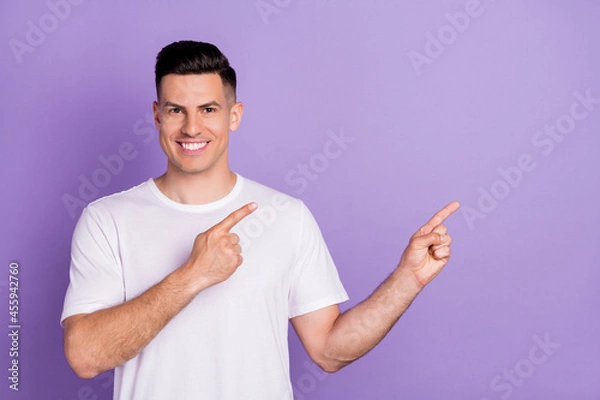 Fototapeta Photo of positive happy young man point fingers empty space information isolated on purple color background