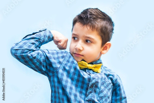 Obraz boy shows strength with a gesture. portrait of a beautiful boy on a blue background