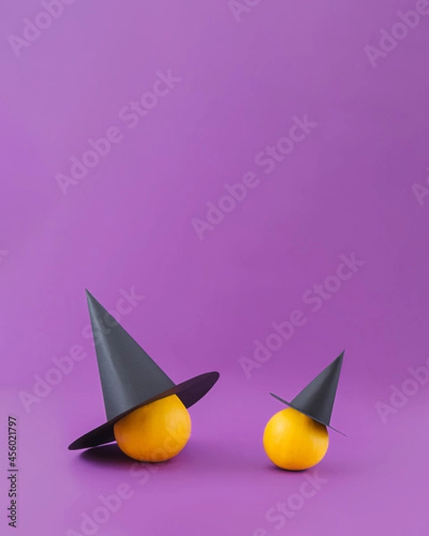Fototapeta Big and small pumpkin squashes wearing witch hats. Fun minimal Halloween card idea with copy space.