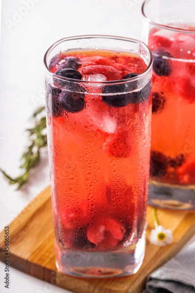 Fototapeta Two tall glasses with red fruits juice on ice