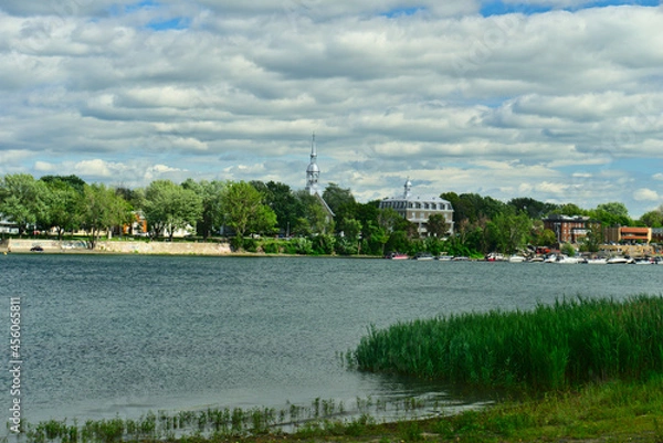 Fototapeta The marina of Boucherville at islands of Boucherville national park in Lawrence (Laurent) River, Montreal, QC on a cloudy summer day. The trees and grass on the river banks.