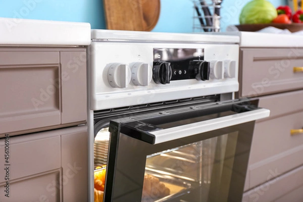 Fototapeta Modern electric oven with croissants in kitchen, closeup