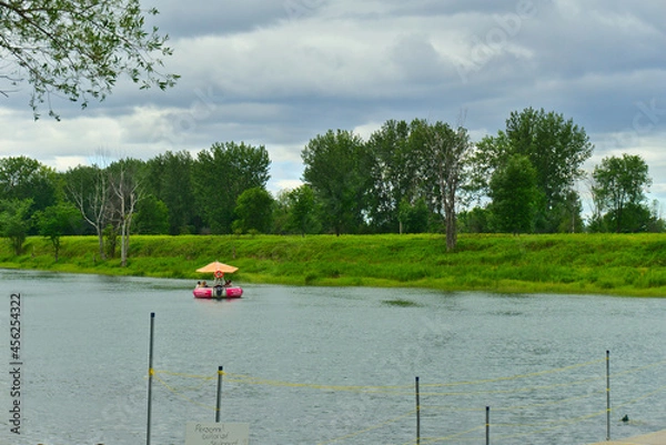 Fototapeta Boucherville, QC, Canada, 7-30-2021, a group of people on a donut boat in Lawrence (Laurent) River, islands of Boucherville national park on a cloudy summer day. Family, fun, together, team concepts.