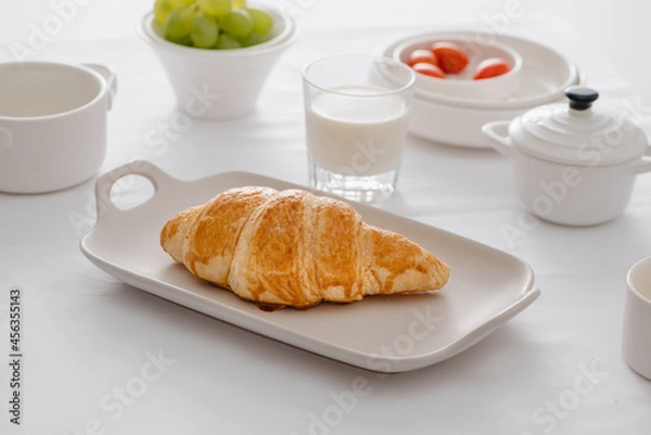 Fototapeta Breakfast served with croissants, fresh grapes, eggs, tomato, milk, butter and orange jam