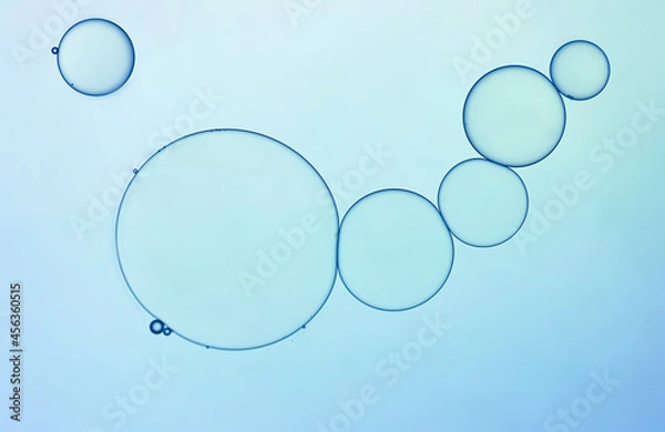 Fototapeta Abstract oil droplets create shapes and pattern on light blue  backgrounds.