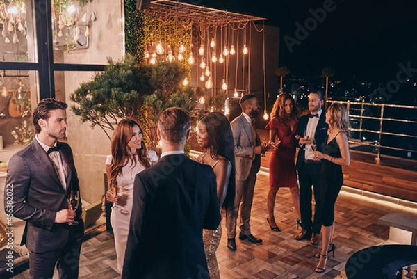 Fototapeta Group of people in formalwear communicating and smiling while spending time on luxury party