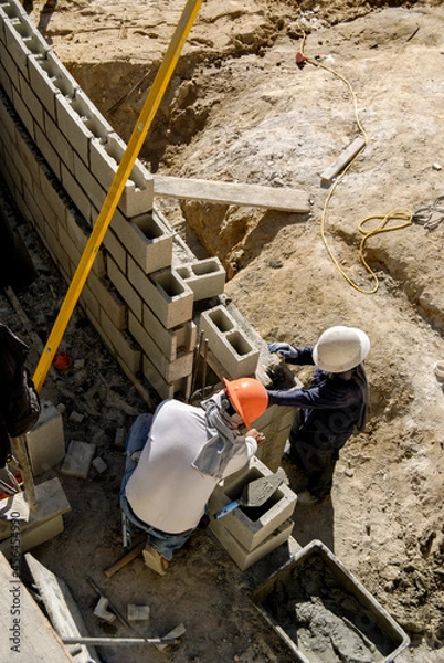 Fototapeta Block masons building a retaining wall