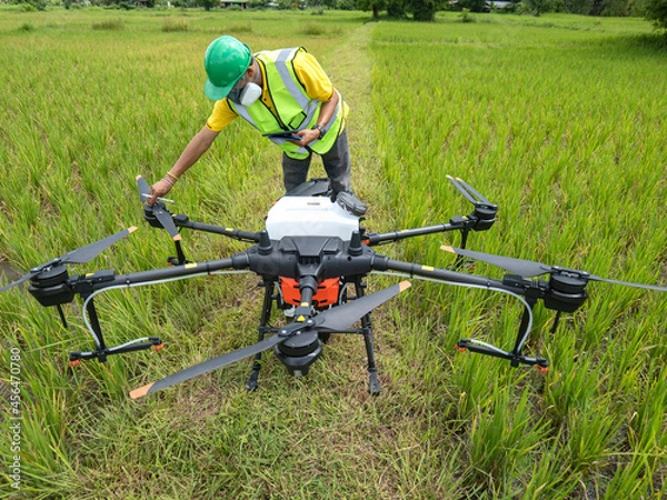 Obraz Farmer technicians prepare to remotely fly agricultural drones to fly to spray fertilizer in rice fields. Agricultural technology smart farm concept.