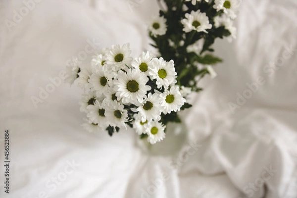 Obraz bouquet of white flowers in bed bedroom with  natural bed sheets blanket 
crumpled