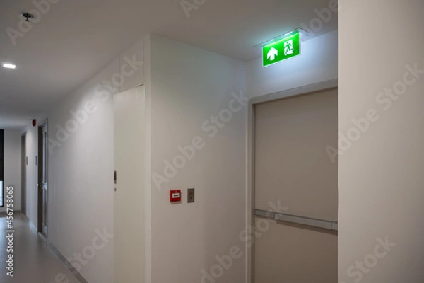 Fototapeta Green fire exit sign over the exit door in the building.