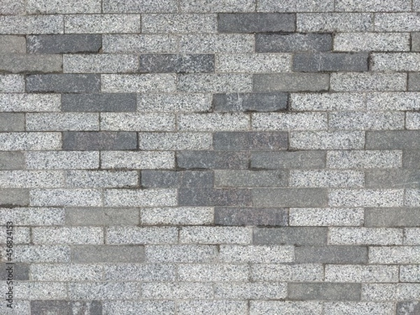 Fototapeta masonry of small long gray bricks of different shades. tile pattern on the roads. road surface