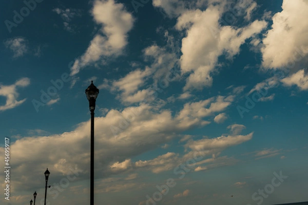 Obraz Street lamps in foreground of sky background, lined up at an angle. 