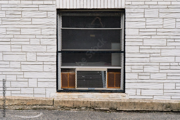 Obraz Closeup of basement window with old dilapidated air conditioner, surrounded by brick wall detail. 