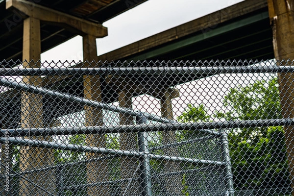Obraz View of security chain link fences and highway overpasses overlaid in foreground and background. 