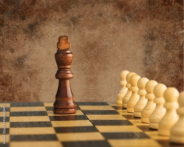 Fototapeta Wooden chess pieces facing each other on a vintage chessboard. Rivalry concept,