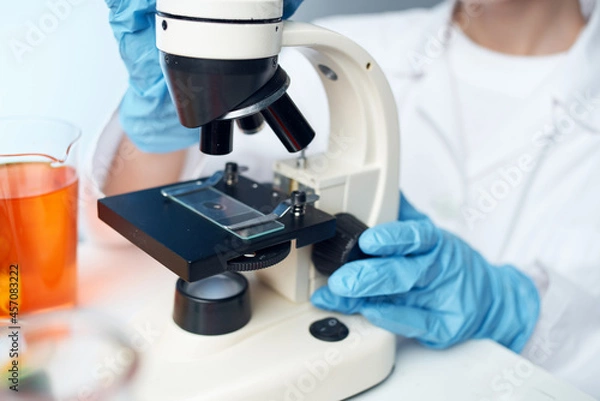 Fototapeta laboratory assistant sitting at the table microscope research Studio