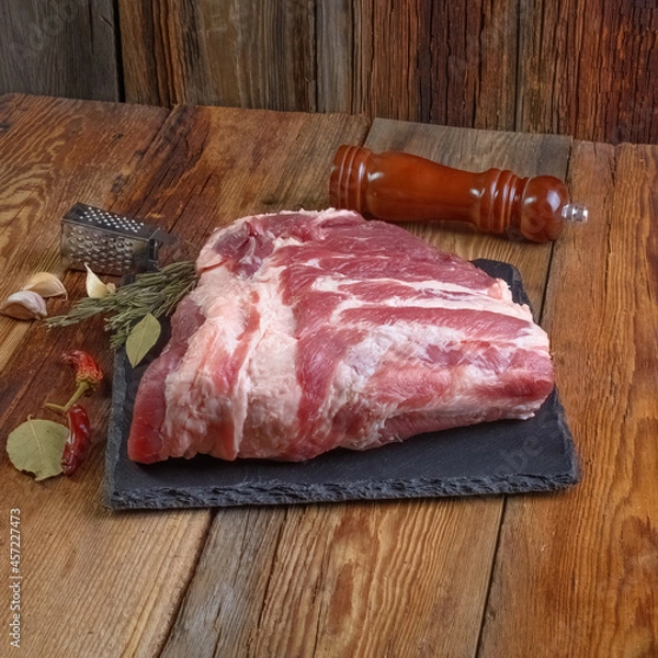 Fototapeta Raw pork ribs are laid out on a cutting board.Spices for cooking meat dishes close-up.Selective Focus.