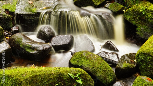 Fototapeta Slowmotion waterfall splashing onto rocks 