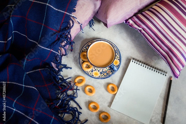 Fototapeta Autumn composition. Coffee notepad plaid top view flat lay. The concept of comfort, autumn winter cold. A mockup for writing, a white sheet of a notebook. Cozy still life with a blue blanket, pillows