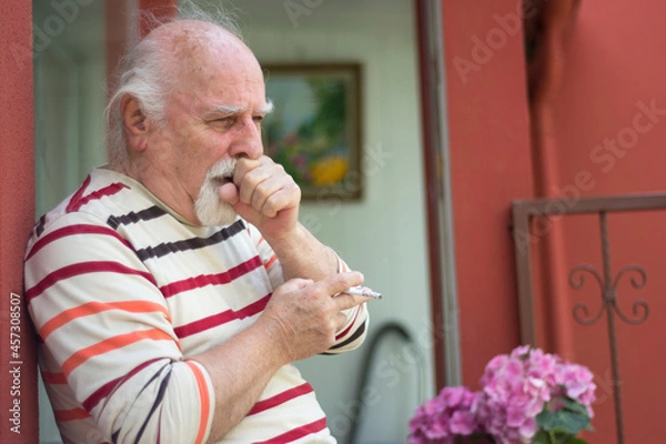 Fototapeta Retired old man smoking and coughing. an unhealthy life. Selective Focus 