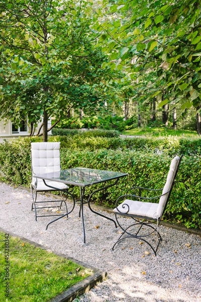 Obraz Beautiful chairs in the garden with small glass table. Nobody. Breakfast in the green park. 
