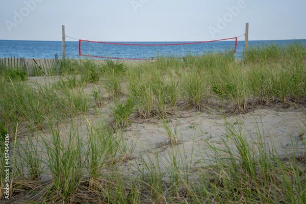Obraz View from boardwalk overlooking grass and beach volleyball net, ocean in distance. 