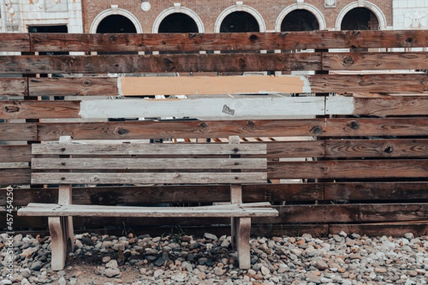 Obraz Bench with similar fence & painted board shapes behind it.  Arched building architecture in the background. 