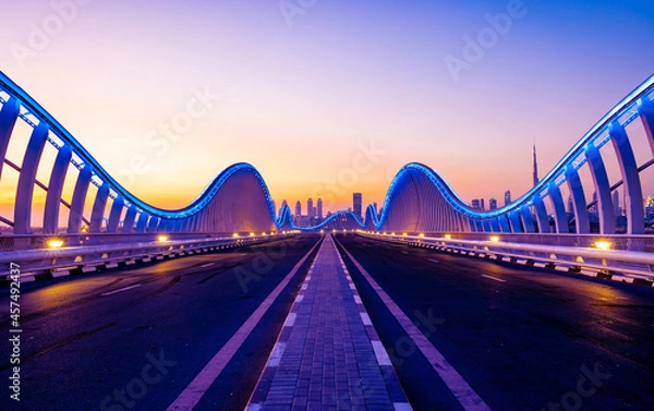 Fototapeta Beautiful view of Meydan Bridge in Dubai. Modern artistic bridge in Dubai. Night architectural shot of a bridge with curvy blue lights.