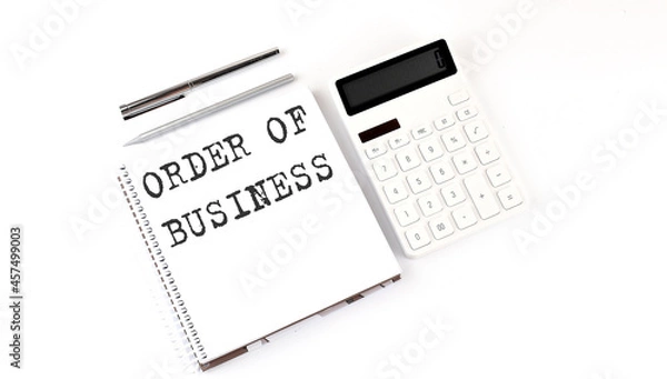Fototapeta Notepad with text ORDER OF BUSINESS with calculator and pen. White background. Business concept