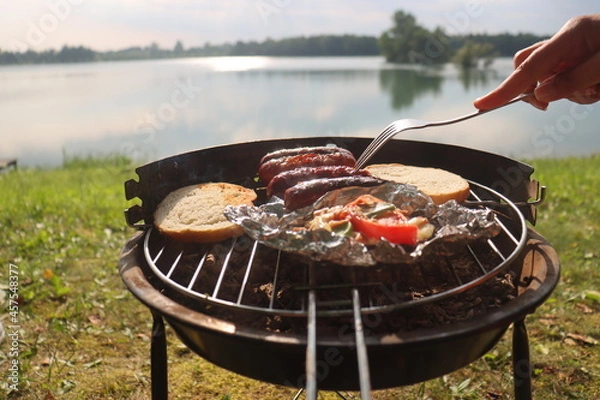 Obraz grilled sausage at the summer camp. Vacation in nature near the lake in the early morning