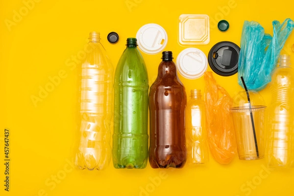 Fototapeta Heap of plastic disposable packaging and disposable tableware on yellow background. Concept of zero pollution and eco-friendly.