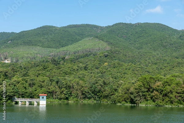 Fototapeta The scenery beside the reservoir is blue sky, white clouds, green mountains and clear water