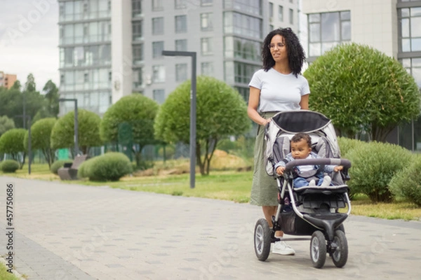Obraz A young black mother walks with her child, who is sitting in a stroller