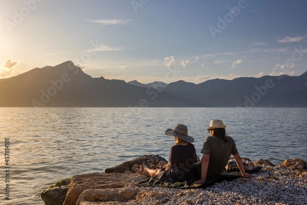 Obraz Italy - Lake Garda in the town of Torri del Benaco. A sunset, a romantic couple by the water, in the distance you can see the mountain peaks.